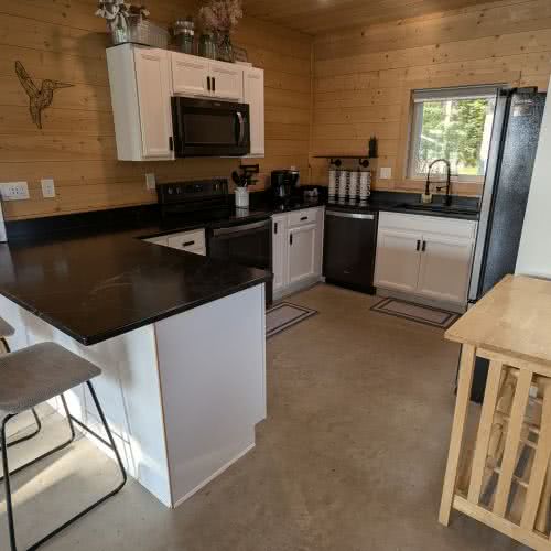 &Eacute;clairage encastr&eacute; et meubles de cuisine modernes dans notre cuisine enti&egrave;rement &eacute;quip&eacute;e, cr&eacute;ant un espace lumineux et accueillant pour cuisiner dans la maison au bord du lac.